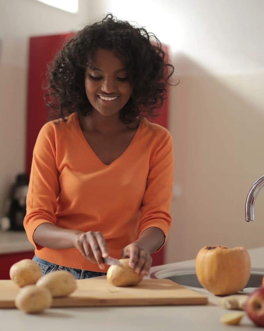 Une cuisinière découpe des légumes dans une cuisine